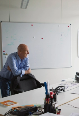 Business professional standing in a modern office, leaning on a chair and looking out