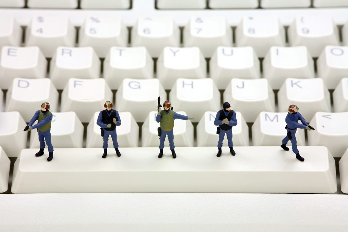 Miniature swat team is standing on a computer keyboard guarding it from viruses, spyware and identity thieves. Computer security concept.